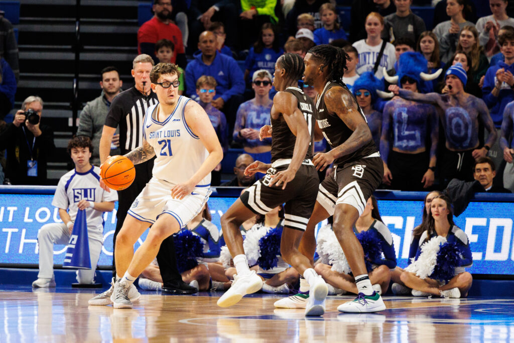 St. Louis' junior center Robbie Avila drives to the basket while the Bonnies' Melvin Council Jr. and Noel Brown defend